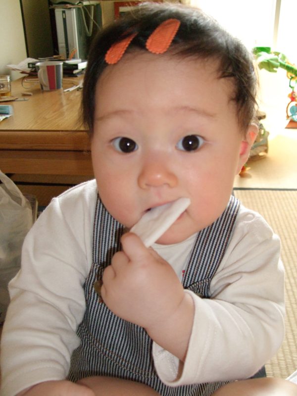 おせんべいをくわえた赤ちゃん